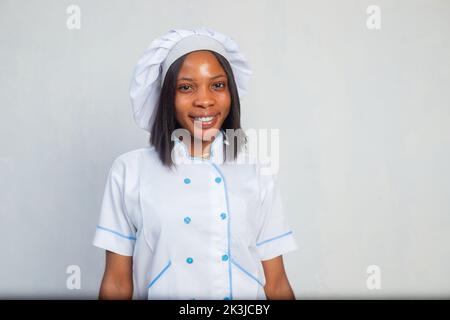 Un ritratto di una giovane cuoca nera sorridente Foto Stock