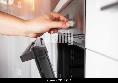 La mano di un uomo seleziona una funzione in un moderno forno elettrico e imposta la protezione del bambino. Foto Stock