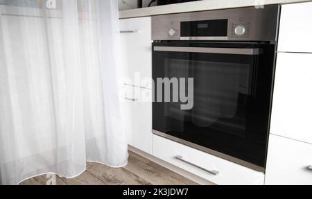 Moderno forno elettrico nero costruito in una cucina bianca. Forno multifunzione con griglia, retroilluminazione telecamera Foto Stock