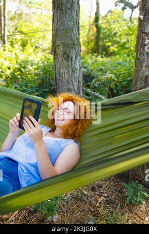 Una donna che acquista online per il Black Friday dalla comodità di un'amaca Foto Stock