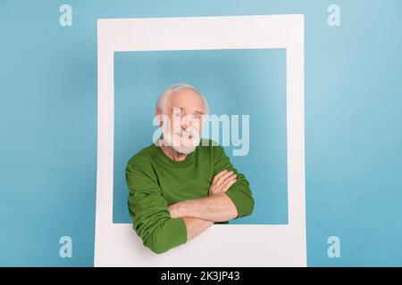 Foto di una persona amichevole positiva incrociata braccia toothy sorriso guardare attraverso la scheda album isolato su sfondo di colore blu Foto Stock