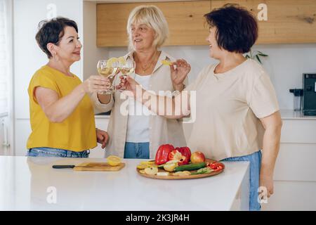 Grazie. Gruppo di belle donne di mezza età che si godono un brindisi celebrativo insieme in una casa. Foto Stock