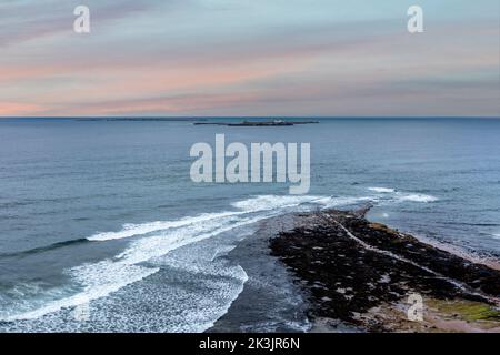 vista rialzata delle isole farne dalla spiaggia di bamburgh al tramonto Foto Stock