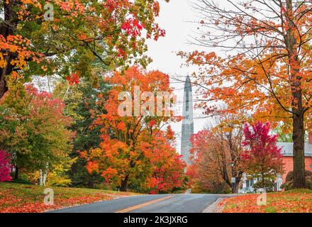 Una vista del monumento di battaglia di Bennington, Vermont, dietro una strada e alberi colorati di autunno caduta Foto Stock