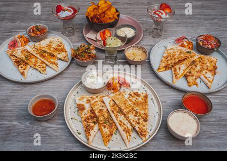 Una vista ad angolo alto di fette di Quesadilla e salse su un tavolo Foto Stock