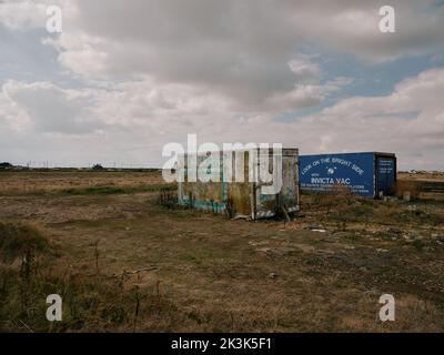 Guardate sul lato luminoso - vecchi container riproposti per immagazzinare reti da pesca e attrezzature da pesca su Dungeness Kent Inghilterra UK - strano paesaggio eccentrico Foto Stock