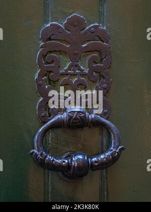 Vista in primo piano del tradizionale knoccer porta in ottone vintage con facciata stilizzata isolata su antica porta in legno verde bronzo, Montpellier, Francia Foto Stock