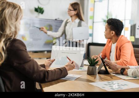 Concentrarsi sulla gestione del rapporto finanziario mani. Direttore aziendale femminile con computer portatile in mano per incontri di lavoro con colleghi internazionali. Vari diagrammi, grafici e tecnologia in ufficio. Foto Stock