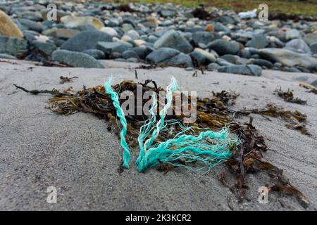 Detriti di corda di plastica che si stagliano su una spiaggia con alghe sulla costa di Donregal, Irlanda Foto Stock