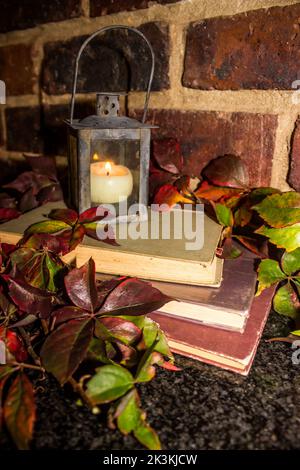 Still-life rustico di una pila di vecchi libri e di un portacandele a forma di lanterna Foto Stock