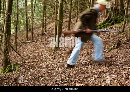 Un'immagine blurida di un uomo che cammina attraverso i boschi è una pistola Foto Stock