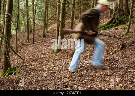 Un'immagine blurida di un uomo che cammina attraverso i boschi è una pistola Foto Stock