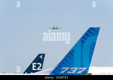 Tails of Boeing 737 MAX 10 and Embraer E190-E2 Airliner jet plane at the Farnborough International Airshow 2022, with executive jet plane on finals Foto Stock