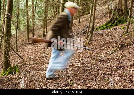 Un'immagine blurida di un uomo che cammina attraverso i boschi è una pistola Foto Stock