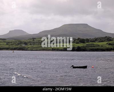 Le colline Macleod's Table Nord e Sud con una barca da pesca sul Loch Dunvegan da vicino al molo privato presso Dunvegan Castle, Isola di Skye, Scozia. Foto Stock