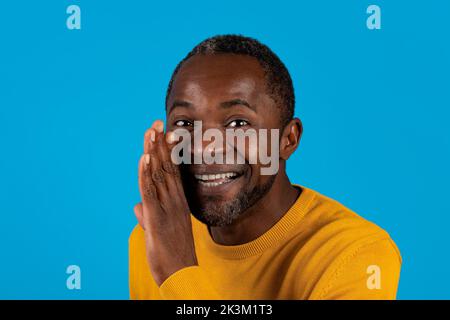 Bell'uomo nero che tiene la mano accanto alla bocca Foto Stock