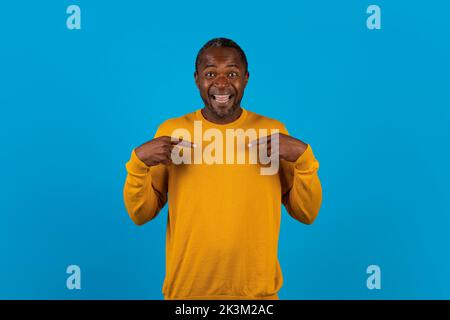 Un bell'uomo nero eccitato che guarda sorpreso indicandosi Foto Stock
