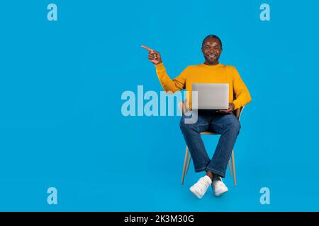 Uomo afro-americano positivo che lavora online, usando il laptop Foto Stock