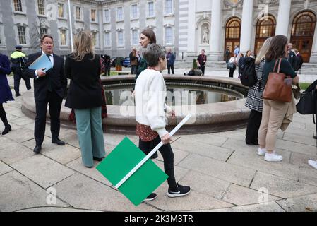 Il ministro degli alloggi Darragh o'Brien (a sinistra) parla con i giornalisti mentre il fuoco marshall (centro) cammina con un cartello al di fuori degli edifici governativi a Dublino dopo che è stato evacuato a causa di un allarme antincendio durante una conferenza stampa per il Dipartimento degli alloggi, il governo locale e il patrimonio. Data immagine: Martedì 27 settembre 2022. Foto Stock