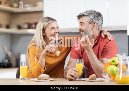 Uomo e donna allegri che hanno uno spuntino e parlano a casa Foto Stock