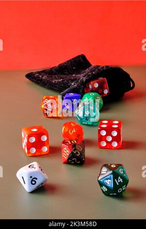 Dadi di gioco di ruolo diversi sulla parte superiore di un tavolo con uno sfondo rosso. Foto Stock