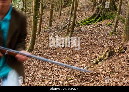 Un'immagine blurida di un uomo che cammina attraverso i boschi è una pistola Foto Stock