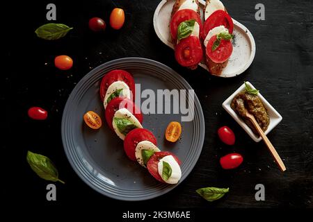 Insalata di caprese italiana con mozzarella fresca, pomodori, basilico e pesto con antipasto a sandwich con insalata di caprese . Vista dall'alto del cibo. Antipasto classico rustico. Foto Stock