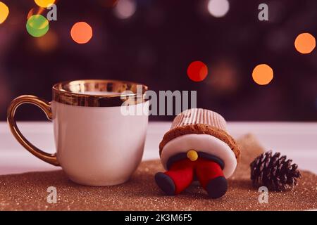Accogliente tè di Natale. Tortini decorativi e una tazza di tè davanti all'albero di Natale. Buon umore, umore festivo. Messa a fuoco selettiva Foto Stock
