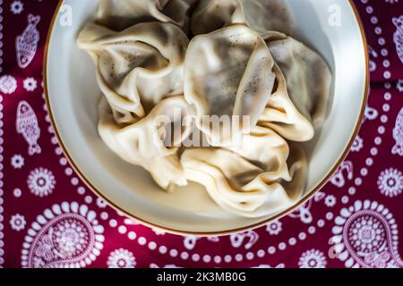 I khinkali georgiani sono serviti nella ciotola su una tovaglia Supra tradizionale ricoperta di spezie al pepe nero Foto Stock
