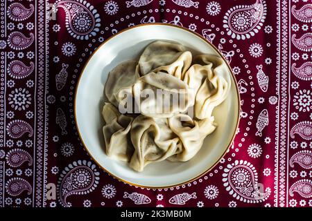 I khinkali georgiani sono serviti nella ciotola su una tovaglia Supra tradizionale ricoperta di spezie al pepe nero Foto Stock