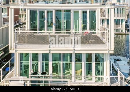 Dall'alto, vista esterna di una moderna casa vetrata accanto ai canali d'acqua in una giornata di sole Foto Stock