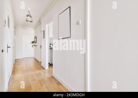 Porte chiuse bianche in corridoio chiaro con cornici decorative alle pareti in un elegante e moderno appartamento con lampada luminosa Foto Stock