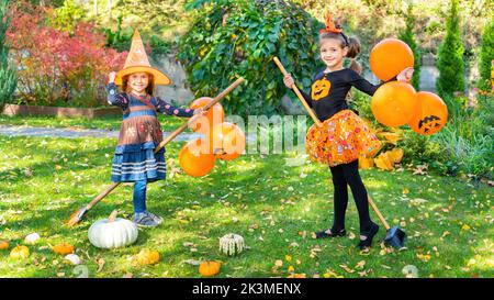 I capretti felici giocano le streghe del bastone nel cortile posteriore su Halloween. Idee di attività per i bambini per la festa di Halloween. I bambini allegri si ingannano e giocano l Foto Stock