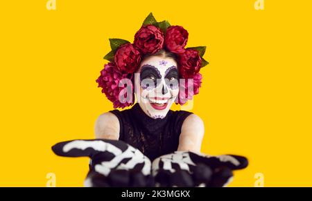 Donna felice vestita per Halloween o Day of the Dead sorridendo e stretching mani alla macchina fotografica Foto Stock