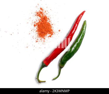 Il pepe verde e il pepe rosso macinato sono isolati. Pepe piccante su fondo bianco. Ingrediente per un piatto che brucia. Paprika sparsi sul tavolo Foto Stock