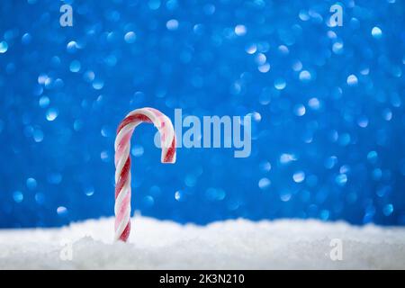 Caramella di Natale su sfondo bokeh blu e neve caduta. Cartolina Felice anno nuovo, Natale, Buon San Valentino. copia spazio Foto Stock
