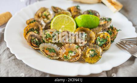 Molluschi di limbano con calce su piatto bianco Foto Stock
