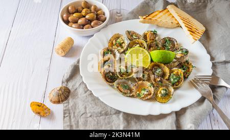 Molluschi di limbano con calce su piatto bianco Foto Stock