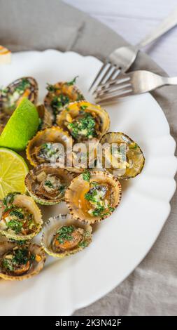 Molluschi di limbano con calce su piatto bianco Foto Stock