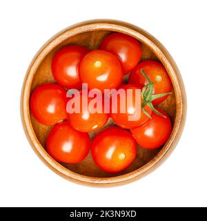 Pomodori ciliegini, in una ciotola di legno. Tipo fresco e maturo di pomodori da cocktail rossi, piccoli e tondi, Solanum lycopersicum var. Cerasiforme. Foto Stock