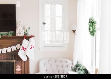 Calze sul caminetto all'interno della casa decorata per natale. Foto Stock