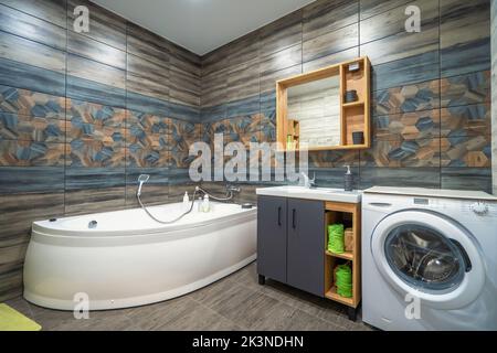 Moderno bagno interno con vasca, specchio, lavabo e lavatrice. Foto Stock