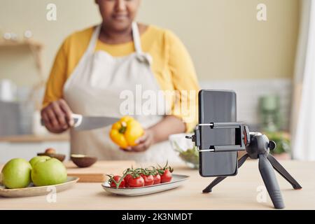 Donna nera che filma video di cucina in cucina, concentrarsi sullo smartphone sul treppiede, spazio di copia Foto Stock