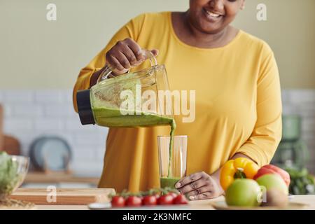 Primo piano di sorridente donna nera godendo sano frullato in cucina di casa, spazio copia Foto Stock