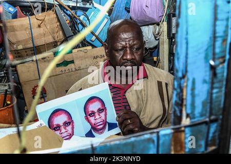 Nakuru, Kenya, 27/09/2022, Josephat Mureithi, tiene ritratti di suo fratello ucciso, William Munuhe, nel suo laboratorio di elettronica a Nakuru Town. Guidato da Josephat, la famiglia del defunto William Munuhe che è stato ucciso il 14 gennaio 2003, come ha aiutato la polizia e l'Ufficio federale delle indagini (FBI) per rintracciare il genocidio ruandese fuggitivo, Felicien Kabuga, è ancora in cerca di giustizia 19 anni dopo. Felicien Kabuga (89), è stato cacciato dal suo nascondiglio in Francia dopo 26 anni dalla fuga e sarà presentato al UNís meccanismo internazionale residuo per i tribunali penali a l'Aia ad un Foto Stock