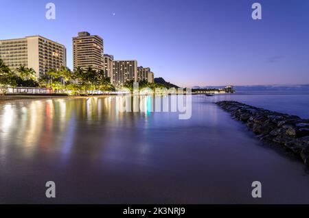 La luce pre-alba lungo Waikiki Beach guardando verso Diamondhead Mountain all'alba a Oahu, Hawaii Foto Stock