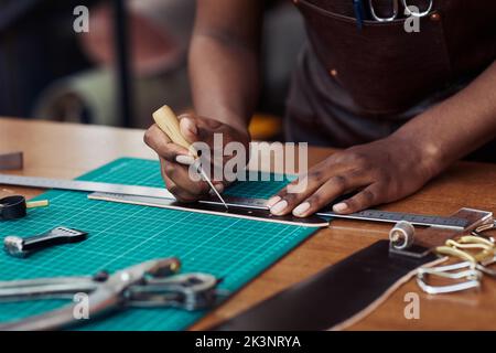 Primo piano di buchi artigianali neri in cintura artigianale in bottega di pelletteria, spazio copia Foto Stock