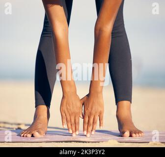 Lo yoga la mantiene in forma. Una donna irriconoscibile che pratica lo yoga sulla spiaggia. Foto Stock