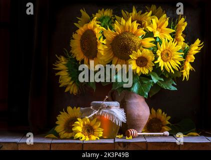 Bel giallo girasole ancora vita bouquet in una caraffa di argilla ceramica rustico stile olio miele Foto scuro sfondo tavolo in legno Vintage. Tasto basso retro Foto Stock