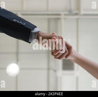 Closeup i partner commerciali si stringono le mani, celebrando il successo aziendale in un ufficio moderno con soffitto alto. Vista dal basso Foto Stock